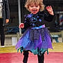 toddler, child, girl, curly_hair, purple_dress, blue_dress, spider_web, outdoor, playful, jumping, smiling, happy, person, fashion, costume, leggings, fun, movement, joy, blurred_background