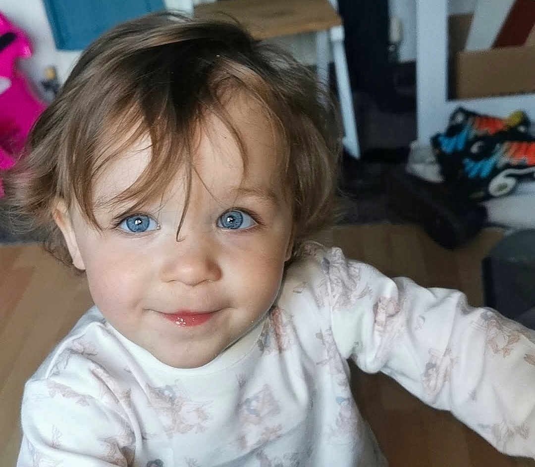 Stella is registered to the contest to win money with this photo: toddler, child, blue_eyes, smiling, indoor, person, face, hair, sweater, cute, young_child, portrait, happy, skin, looking_at_camera, baby, head, expression, clothing, human
