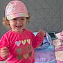blur, carpet, child, colorful, curly_hair, cushion, happy, hat, heart, indoor, motion, person, pink_clothing, playful, plush, smile, tablet, toddler, unicorn, young_child