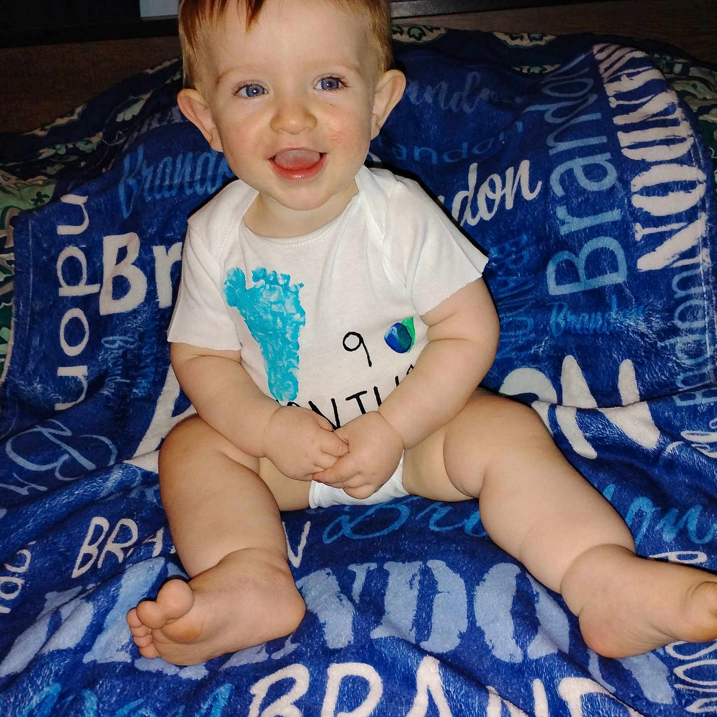 Brandon joined the competition — help win amazing prizes! baby, child, smiling, blue_eyes, white_onesie, blanket, sitting, happy, indoor, infant, cute, portrait, skin, legs, feet, hands, young, expression, cozy, comfortable