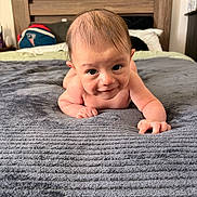 Bryson joined the competition — help win amazing prizes! baby, infant, bed, blanket, blue_blanket, headboard, pillow, wooden_furniture, indoor, person, skin, cute, smile, lying_down, baby_hair, closeup, child, young, room, cozy