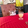 Blue a rejoint le concours — aidez-le/la à gagner de superbes lots ! cat, table, red_tablecloth, glass, juice, chair, living_room, holiday_decorations, clock, furniture, window, stained_glass, indoor, pet, curious, resting, cozy, decor, christmas, relaxing