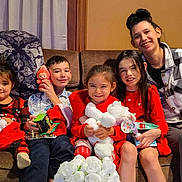 Daniel is registered to the contest to win money with this photo: child, children, family, couch, toys, smile, indoor, blanket, gift, holiday_clothing, happy, person, furniture, young_adult, sitting, red_clothing, plush_toy, curtain, home, portrait