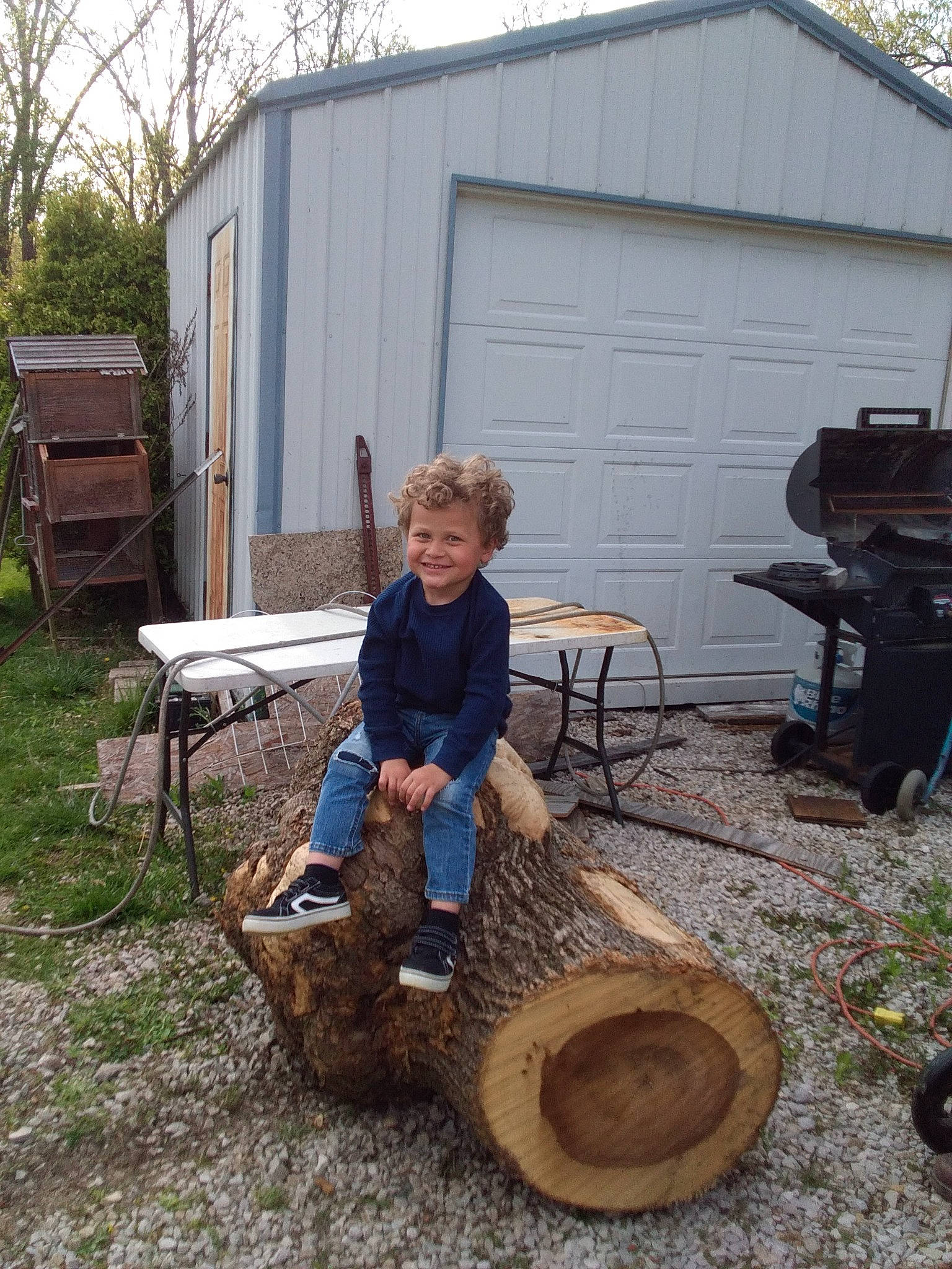 Jordan is registered to the contest to win money with this photo: auto_part, automotive_tire, automotive_wheel_system, chair, grass, hat, house, joy, landscape, leisure, outdoor_furniture, outdoor_table, person, plant, shade, sitting, soil, table, tire, tree