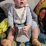 Ishmael is registered to the contest to win money with this photo: baby, child, upseat, bib, socks, chair, couch, pillow, face, surprised, indoor, blanket, clothing, person, home, furniture, sitting, expression, young, cute