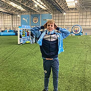 Oscar is registered to the contest to win money with this photo: active, athlete, boy, casual, child, football, green_field, indoor, manchester_city, pose, puma, scarf, shoes, smile, soccer, sport, sportswear, stadium, team_merchandise, young
