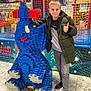 child, boy, lego, lego_sculpture, blue, thumbs_up, jacket, play_area, netting, indoor, shoes, floor, smile, casual_clothing, toy, shopping_mall, entertainment, display, portrait, happy