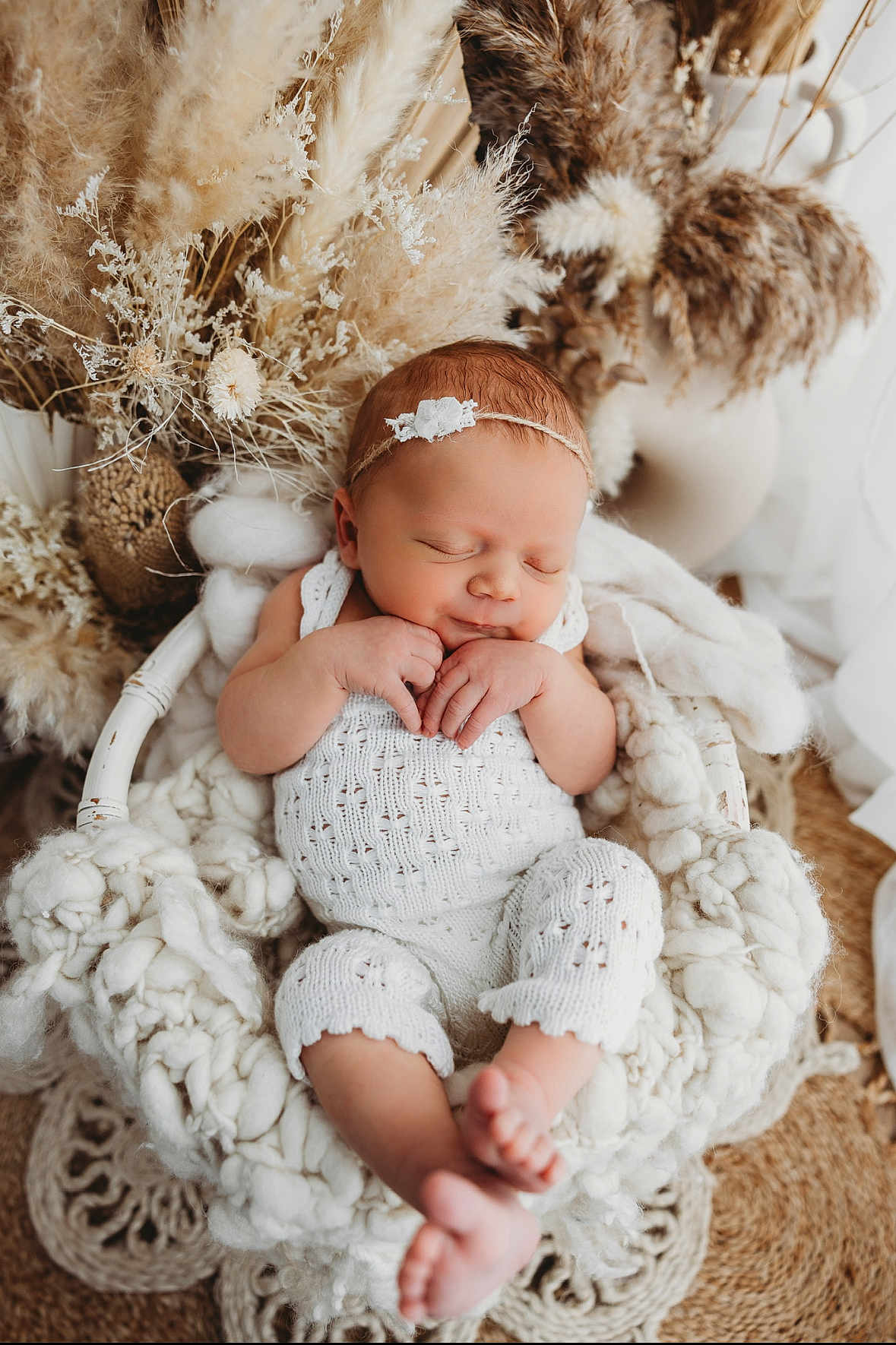 Martina is registered to the contest to win money with this photo: newborn, baby, sleeping, basket, knitted_outfit, white_clothing, hands, feet, headband, dried_flowers, floral_arrangement, cozy, soft_texture, blanket, indoors, peaceful, portrait, cute, infant, rest