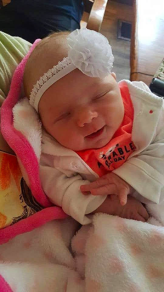 Emma is registered to the contest to win money with this photo: baby, baby_toddler_clothing, cheek, child, comfort, face, fashion_accessory, grass, happy, hat, headwear, linens, lip, nail, peach, person, pink, sitting, skin, smile