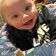 Nevaeh joined the competition — help win amazing prizes! baby, black_sweatshirt, blush, cheeks, closeup, drool, eyes, face, food_stains, happy, infant, mouth, patterned_fabric, play_mat, portrait, seat, skin, smiling, teething, toy