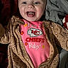 Nevaeh joined the competition — help win amazing prizes! baby, bedding, blanket, brown_jumpsuit, cheeks, close_up, clothing, eyes, face, happy, indoor, infant, kansas_city_chiefs_logo, onesie, patterned_fabric, pink_shirt, portrait, smiling, tongue_out, zipper
