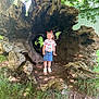 child, girl, tree_root, nature, outdoor, grass, leaves, sunlight, denim_skirt, colorful_shirt, shoes, tree_trunk, smile, playful, wood, forest, daylight, young, standing, casual