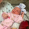 newborn, baby, infant, hospital, person, pink_onesie, hat, bow, sleeping, arm, hand, patterned_gown, face, cute, child, medical, indoor, tiled_wall, cradle, resting