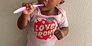 Kehlani joined the competition — help win amazing prizes! brushing_teeth, carpet, child, curly_hair, cute, girl, home, indoor, person, pink_shirt, portrait, red_bow, red_sandals, serious, shorts, standing, toddler, toothbrush, wall, young_child