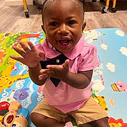 Kehlani joined the competition — help win amazing prizes! toddler, child, pink_bow, pink_shirt, clapping, play_mat, toy, smiling, happy, indoor, nursery, floor, shorts, black_shoes, baby, person, cute, young_child, playful, colorful