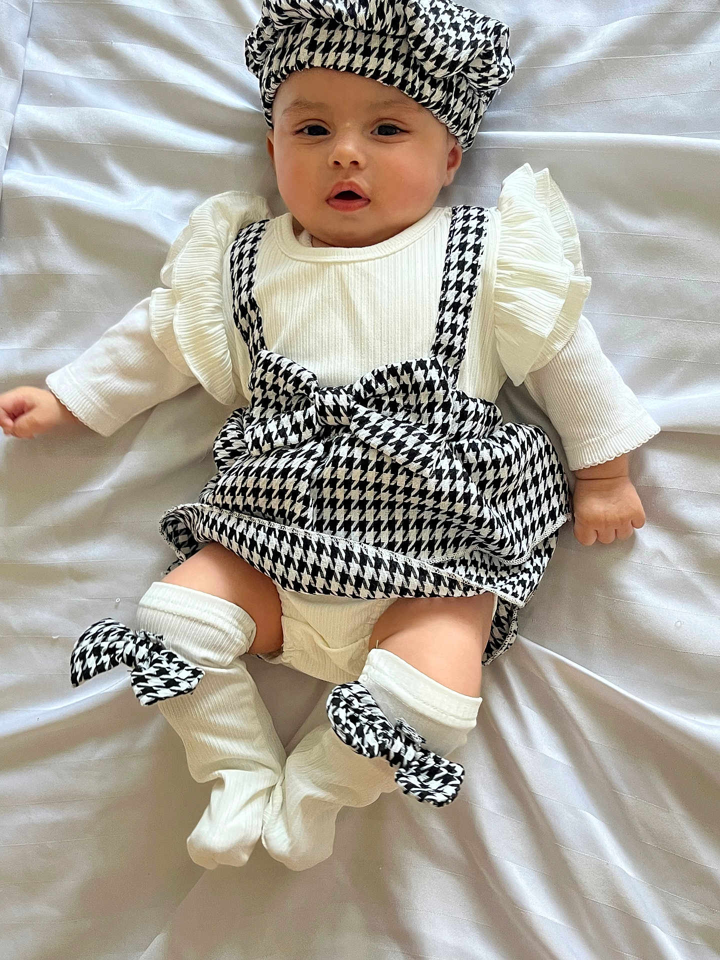 Aylin is registered to the contest to win money with this photo: baby, infant, child, black_and_white, houndstooth, hat, socks, clothing, cute, lying_down, blanket, white, fashion, portrait, face, looking, soft, adorable, small, person