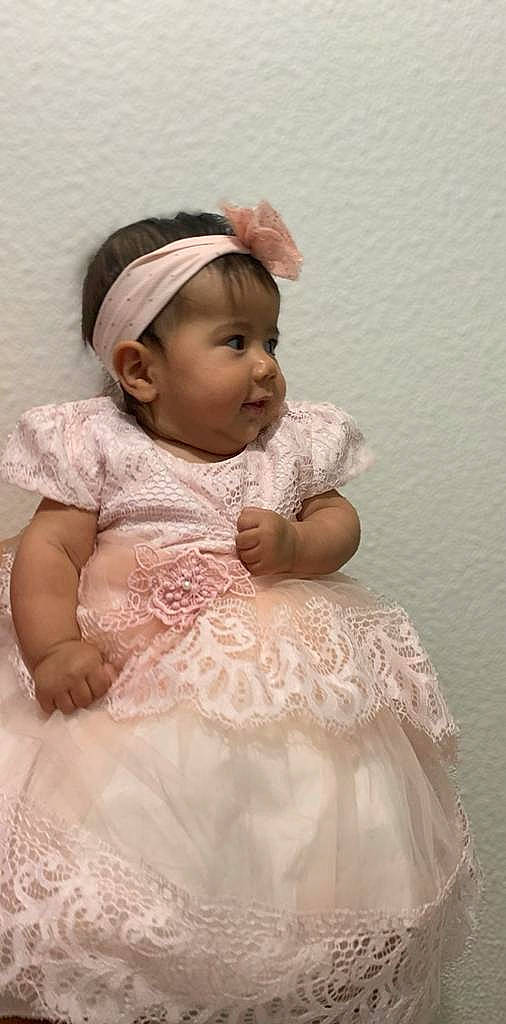 Amira participe au concours pour gagner de l'argent avec cette photo : baby, baby_toddler_clothing, bridal_accessory, child, clothing, day_dress, dress, embellishment, facial_expression, flash_photography, hair_accessory, happy, iris, lip, person, pink, skin, sleeve, standing, textile