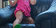 Violet is registered to the contest to win money with this photo: child, smiling, pink_dress, armchair, leather, indoor, window, greenery, happy, playful, curly_hair, person, furniture, casual, portrait, sitting, young_child, home, bright, cozy