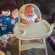 Wraylon is registered to the contest to win money with this photo: baby, blanket, carpet, child, clothing, couch, floor, footwear, furniture, happy, high_chair, home, indoors, living_room, person, pillow, plush_toy, seat, smile, toy
