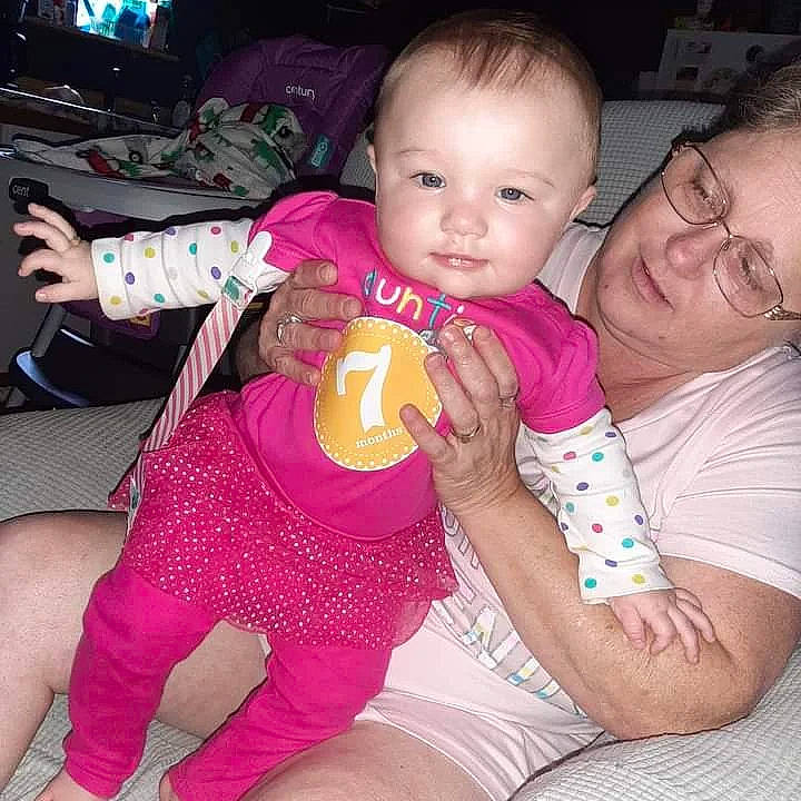 Lillianna Blume is registered to the contest to win money with this photo: abdomen, baby, baby_toddler_clothing, cheek, comfort, finger, fun, happy, head, headwear, lap, leg, mouth, nail, person, pink, skin, smile, thigh, thumb