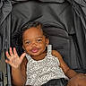 toddler, child, stroller, smiling, waving, leopard_print, clothing, seatbelt, black, cute, happy, baby, portrait, person, sitting, young_child, outdoor, skin, face, hand