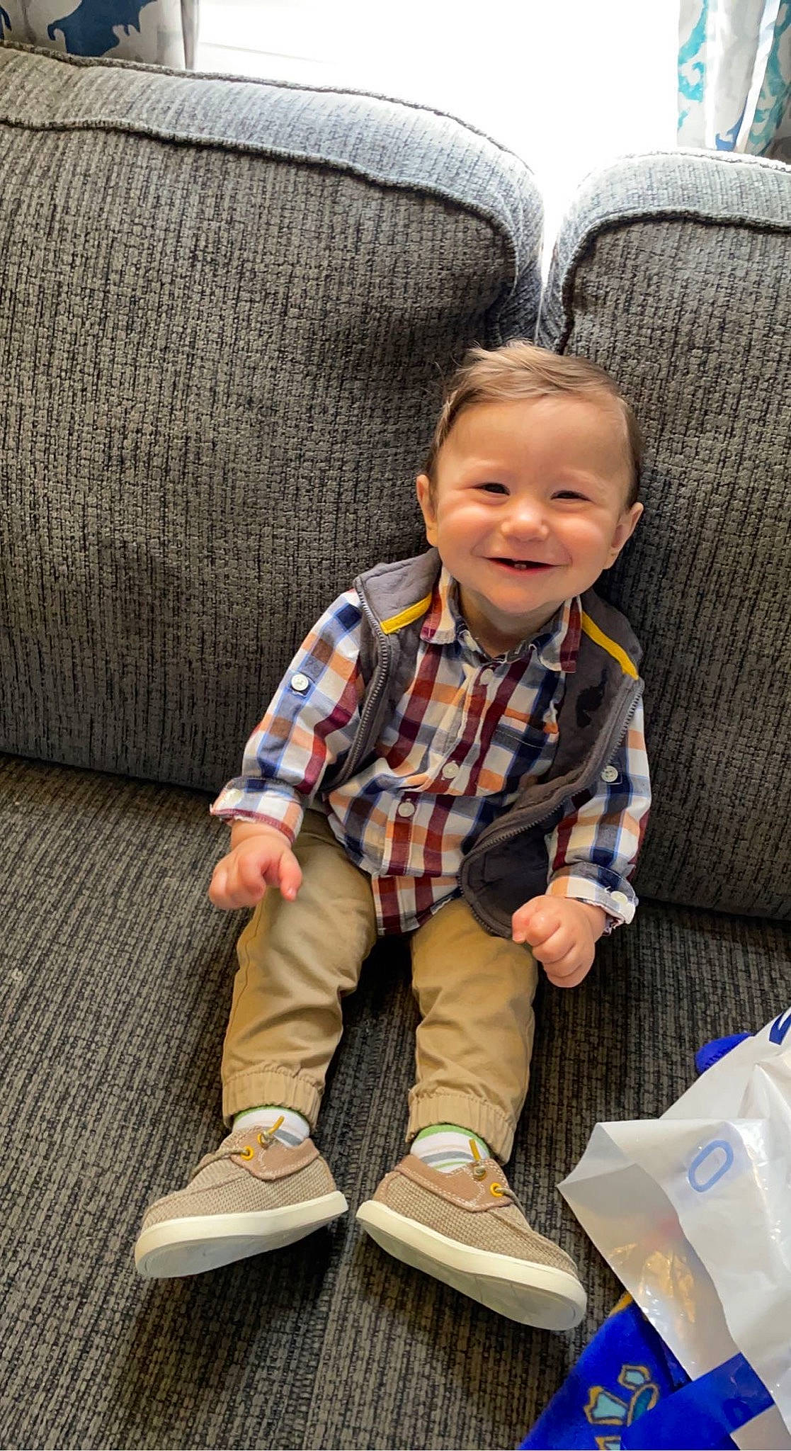 Brentley joined the competition — help win amazing prizes! baby_toddler_clothing, chair, child, comfort, couch, face, flooring, footwear, furniture, joy, outdoor_shoe, pattern, person, plaid, sleeve, smile, sneakers, sock, toddler, walking_shoe