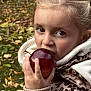 apple, autumn, bite, blonde_hair, brown_eyes, child, cozy, face, food, grass, hand, hoodie, jacket, leaves, nature, outdoor, person, season, snack, young