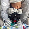 newborn, baby, infant, car_seat, blanket, mittens, hat, sleeping, cozy, stars, moon, pattern, child, cute, peaceful, soft, striped, colorful, fabric, indoors