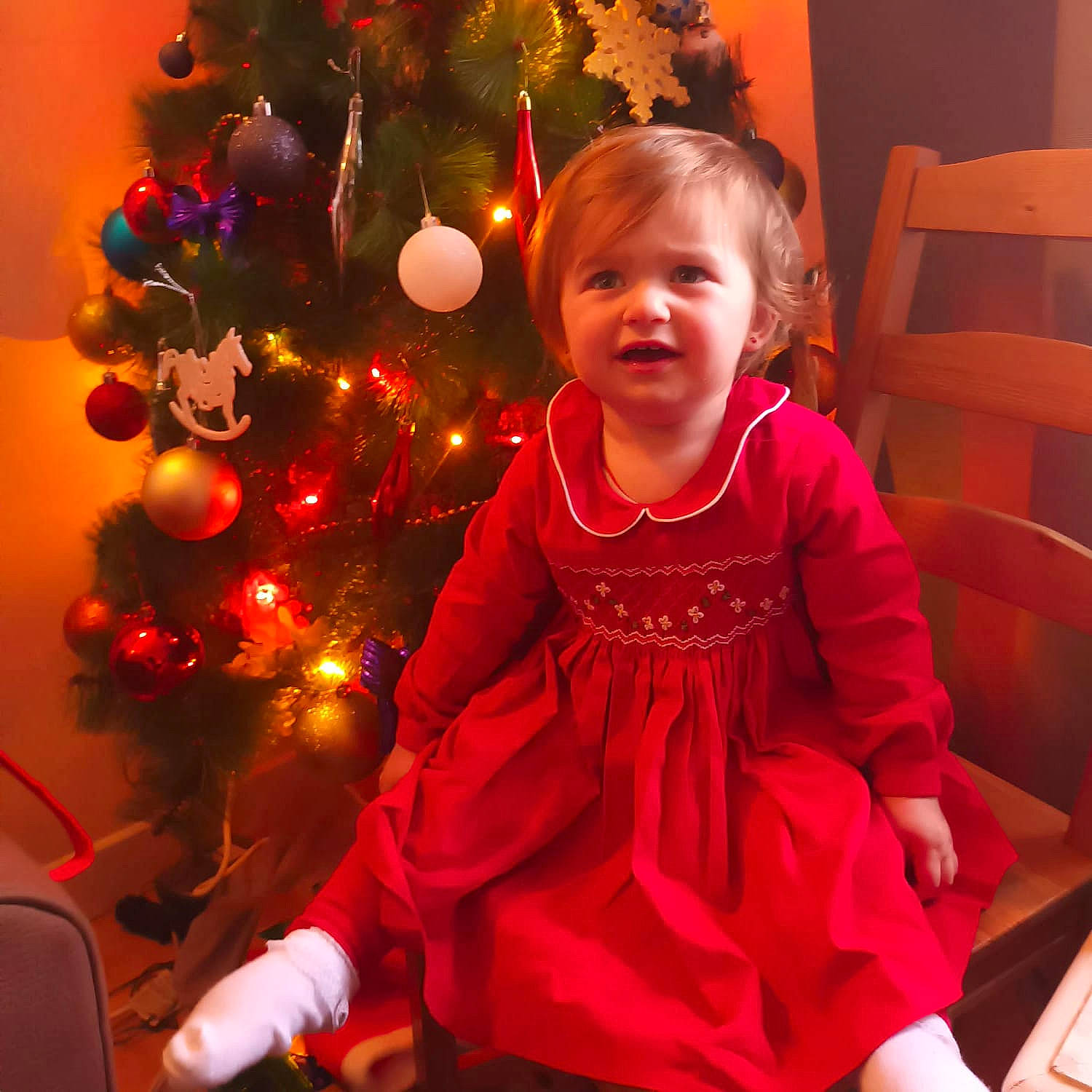 Anaisa participe au concours pour gagner de l'argent avec cette photo : baby_toddler_clothing, child, christmas, christmas_decoration, christmas_eve, christmas_ornament, christmas_tree, conifer, event, evergreen, fun, happy, holiday, holiday_ornament, ornament, person, red, sleeve, smile, standing