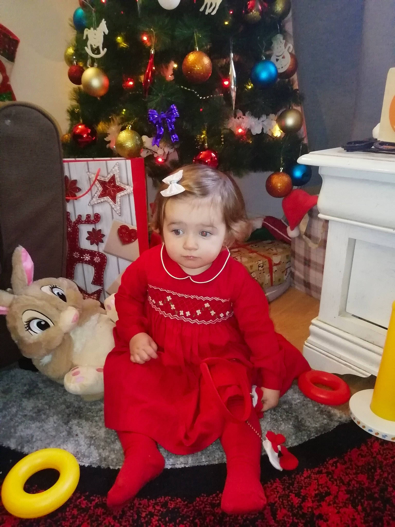 Anaisa participe au concours pour gagner de l'argent avec cette photo : child, christmas, christmas_decoration, christmas_eve, christmas_ornament, christmas_tree, event, fun, fur, happy, holiday, holiday_ornament, interior_design, lap, ornament, person, red, room, toddler, toy