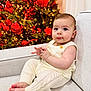 baby, infant, child, knitwear, cream, couch, christmas_tree, red_baubles, lights, holiday, festive, indoors, portrait, sitting, cute, hands, feet, face, warm_lighting, decorations