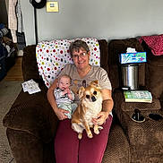 Duane joined the competition — help win amazing prizes! adult, baby, dog, couch, blanket, tissue_box, book, lamp, recliner, glasses, smile, living_room, carpet, envelope, polka_dot, clothing, pet, person, cup_holder, small_dog