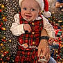baby, child, santa_hat, plaid_outfit, smiling, holiday, christmas_tree, decorations, lights, snowflakes, festive, holding_hand, pacifier, indoor, celebration, happy, person, adult_hand, warm_clothing, seasonal