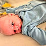 Tommy is registered to the contest to win money with this photo: baby, blanket, blue_onesie, child, close_up, cozy, curious, eyes, face, head, indoors, infant, lying_down, newborn, person, portrait, skin, soft_toys, warm_colors, young