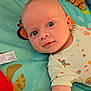 Tommy joined the competition — help win amazing prizes! baby, infant, child, play_mat, toy, plush_toy, colorful, patterned_clothing, face, eyes, arm, lying_down, soft_toys, cute, expression, indoors, closeup, skin, head, smiling