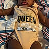 Janylah joined the competition — help win amazing prizes! baby, child, infant, onesie, clothing, face, person, lying_down, blanket, striped, curly_hair, earrings, indoor, cute, calm, soft_lighting, skin, expression, text_on_clothing, young