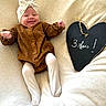 Ana a rejoint le concours — aidez-le/la à gagner de superbes lots ! baby, infant, smiling, brown_outfit, white_tights, headband, heart_shaped_chalkboard, milestone, 3_months, blanket, soft_texture, lying_down, cute, happy, child, portrait, indoors, celebration, baby_clothes, baby_girl