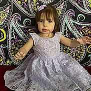 Scarlett joined the competition — help win amazing prizes! toddler, child, dress, lavender, lace, bow, hair, face, pattern, paisley, background, sitting, hands, curious, indoor, portrait, cute, fabric, clothing, young