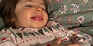 Scarlett is registered to the contest to win money with this photo: toddler, child, smile, happy, hands, bed, blanket, pajamas, christmas_pattern, indoor, cozy, face, person, young_child, sleepwear, cute, expression, holiday, resting, comfort