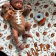 Karter joined the competition — help win amazing prizes! baby, infant, football, hat, socks, blanket, toy, plush, pattern, sports_theme, cute, lying_down, child, soft_toy, cozy, warm, brown, white, decorative, portrait