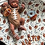 baby, infant, football, hat, socks, blanket, toy, plush, pattern, sports_theme, cute, lying_down, child, soft_toy, cozy, warm, brown, white, decorative, portrait
