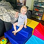 Bentley Kingston is registered to the contest to win money with this photo: toddler, child, smiling, waving, foam_blocks, colorful, indoor, toy_ball, sofa, blanket, drawer, clothing, floor, happy, person, play, step, baby, couch, room