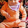 baby, infant, child, smiling, orange_clothing, headband, blanket, patterned_blanket, cozy, cute, sitting, sock, indoors, portrait, young_child, happy, person, soft_fabric, colorful, warm