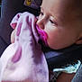 baby, pacifier, blanket, car_seat, toy, infant, child, close_up, warning_label, pink, colorful, seatbelt, face, skin, clothing, cute, indoor, resting, holding, portrait