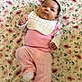baby, child, comfortable, cozy, cute, face, floral_blanket, hands, head, indoors, infant, lying_down, peaceful, pink_clothing, portrait, smile, socks, soft_texture, white_bib, young_child