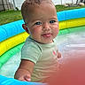 baby, child, pool, water, inflatable_pool, blue_eyes, tongue_out, wet_hair, summer, outdoor, grass, green, playful, cute, infant, sitting, shirt, backyard, daylight, fun