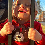 Wyatt joined the competition — help win amazing prizes! child, toddler, smile, sunlight, red_jacket, bear_design, hands, bars, outdoor, daylight, happy, face, clothing, person, playful, fence, suburban, background, tree, head