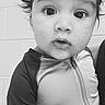 toddler, child, face, portrait, black_and_white, curly_hair, zip_up, clothing, indoor, wall, expression, person, young_child, head_and_shoulders, looking_at_camera, social_media, user_interface, mobile_screen, button_icons, message_bar