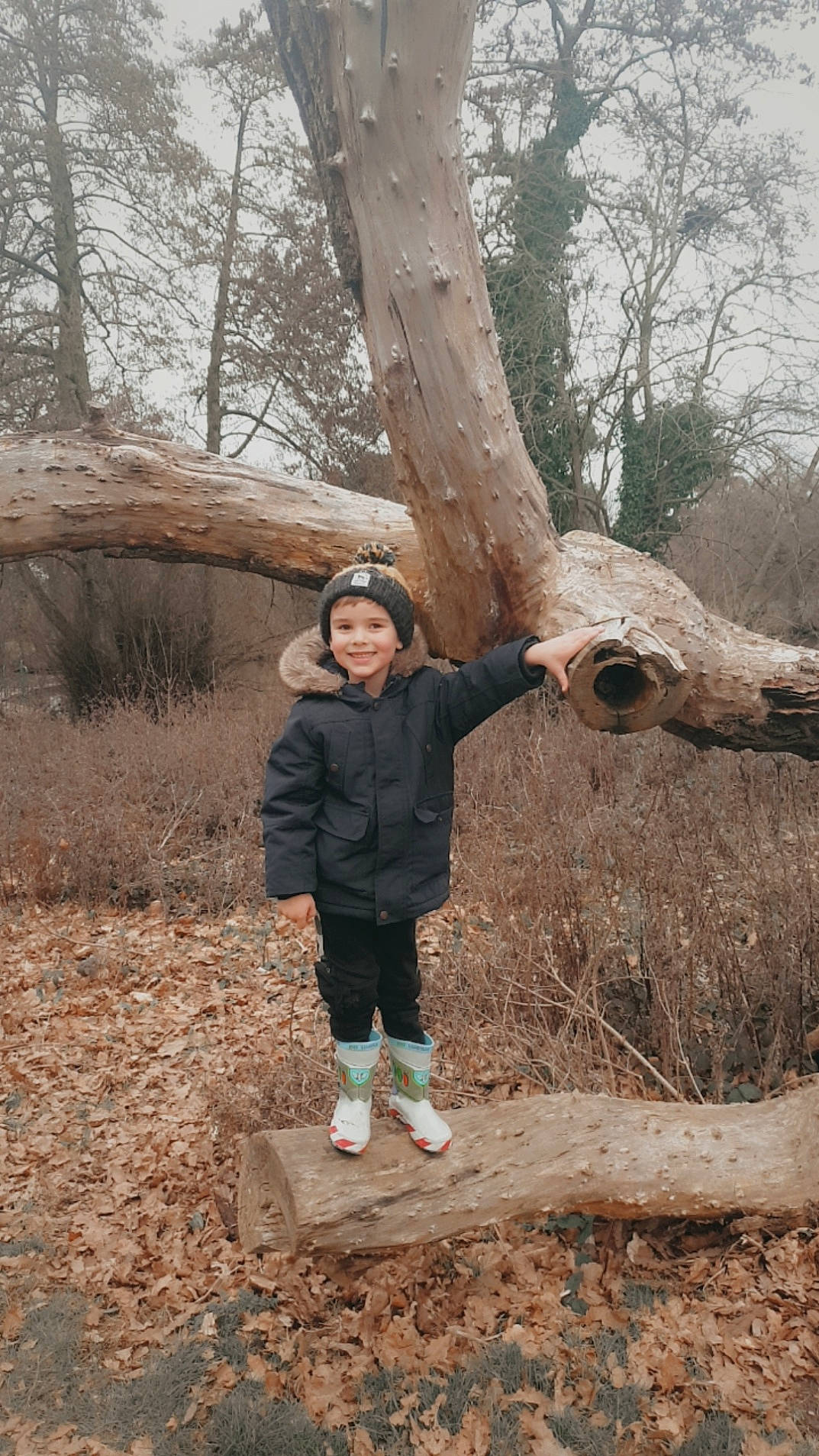 Cody is registered to the contest to win money with this photo: biome, branch, eye, forest, grass, happy, headwear, jacket, joy, leaf, leisure, natural_landscape, people_in_nature, person, plant, sky, spring, toddler, tree, trunk
