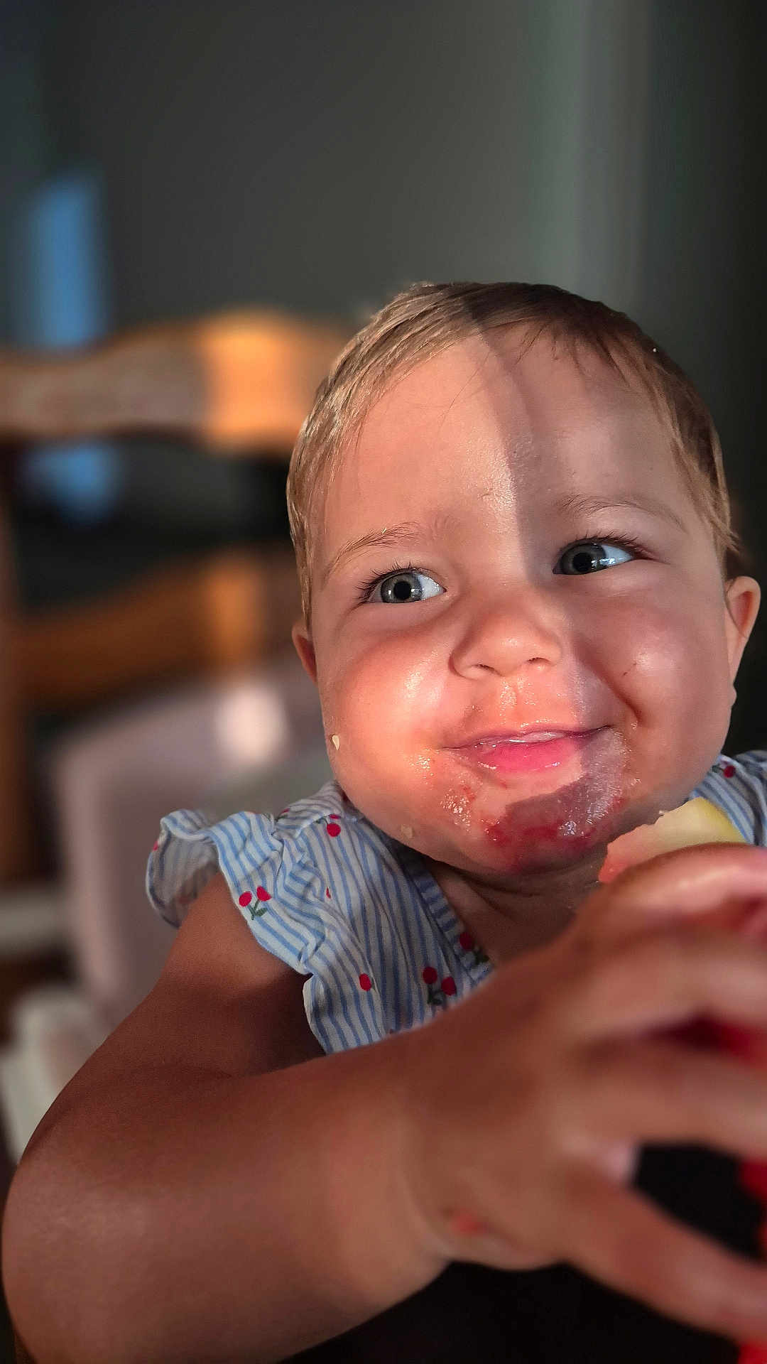 Romy participe au concours pour gagner de l'argent avec cette photo : child, toddler, smiling, messy_face, fruit, eating, sunlight, blue_dress, cherry_pattern, closeup, happy, portrait, baby, hand, skin, indoor, blurred_background, cute, cheeks, expression